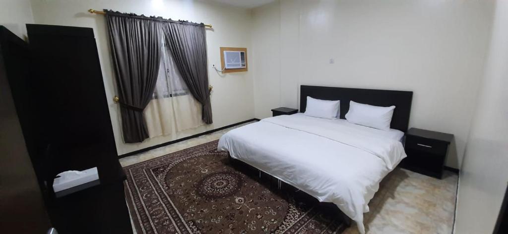 a bedroom with a white bed and a window at شقة مفروشة غرفة وصالة بالمبرز in Al Mubarraz