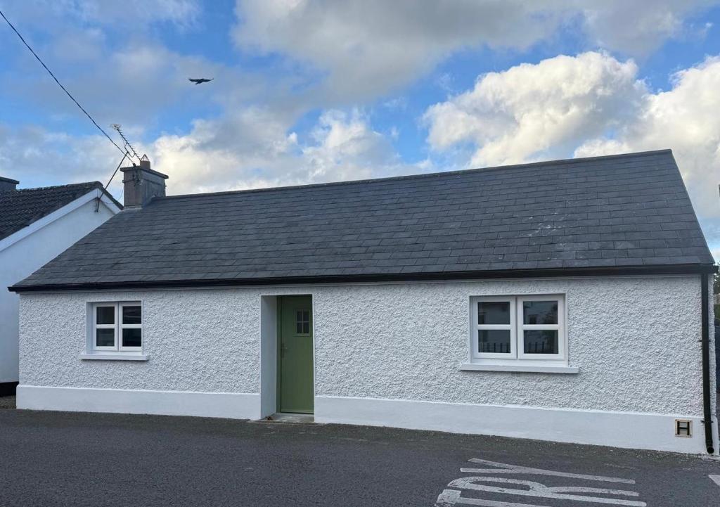 a white house with a green door on a street at McGinns Cottage in Kilcormac