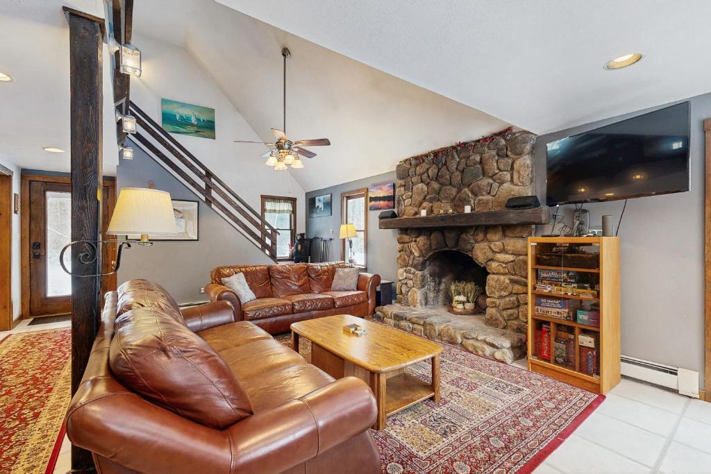 a living room with a leather couch and a stone fireplace at Peaceful Home in North Conway