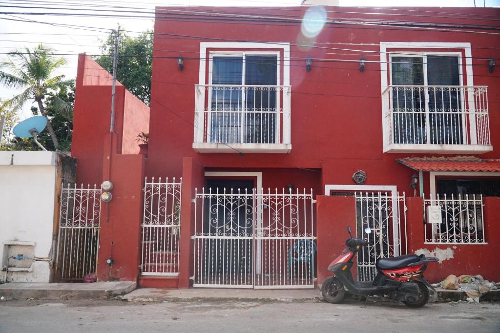 a scooter parked in front of a red house at C 33 Hospedaje Valladolid in Valladolid
