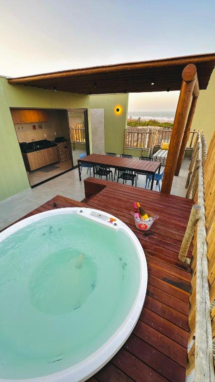 a hot tub sitting on a wooden deck with a patio at Brisa Rooftop Vistamar -Apartamento à beira mar com jacuzzi in Luis Correia