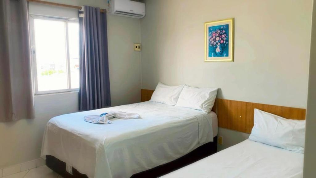 a hotel room with two beds and a window at Pousada Mayer in Paulo Afonso