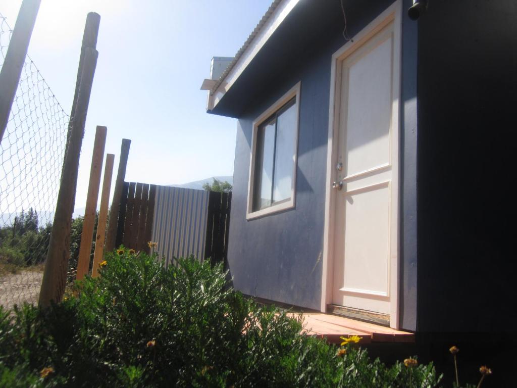 a blue house with a door and a fence at Cabaña Pehuen in San José de Maipo