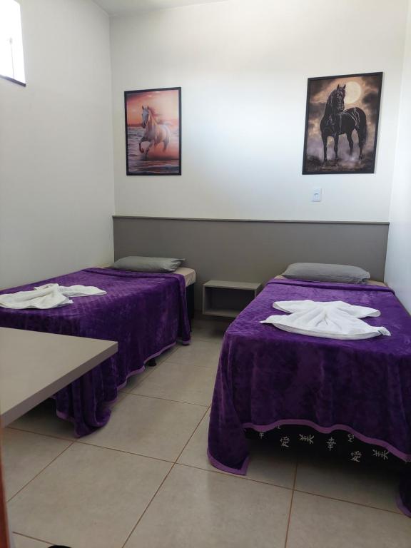 two beds in a room with purple sheets at Quarto Duplo Comercial - Queen's Hotel in Formosa