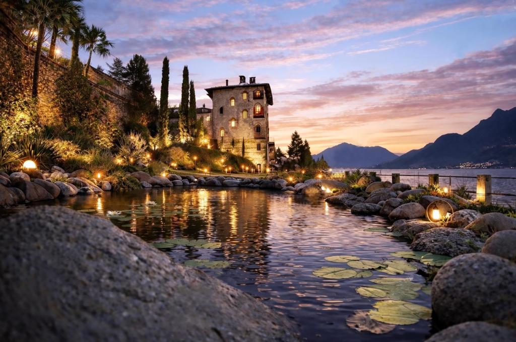 a castle in the middle of a river at sunset at Villa Marina - Como lake in Bellano