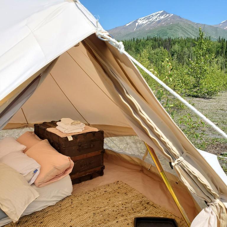 a tent with a bed and a suitcase in it at Alaskan Glamping in Anchorage