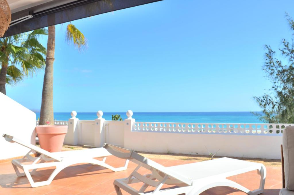 a patio with two chairs and the ocean in the background at Sand & Beach in Pájara