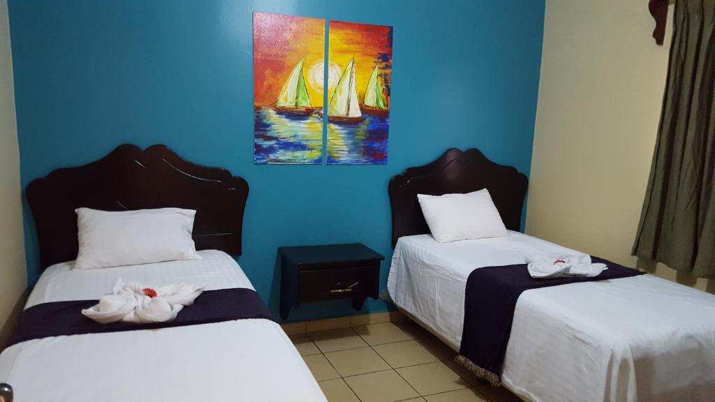 Duas camas num quarto com paredes azuis em Apart Hotel Pico Bonito em La Ceiba