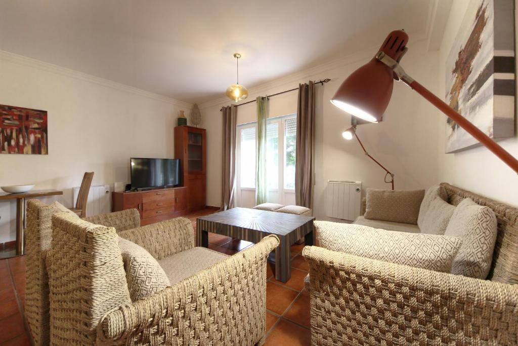 a living room with chairs and a table and a lamp at Apartamento Azur in Vila Nova de Milfontes