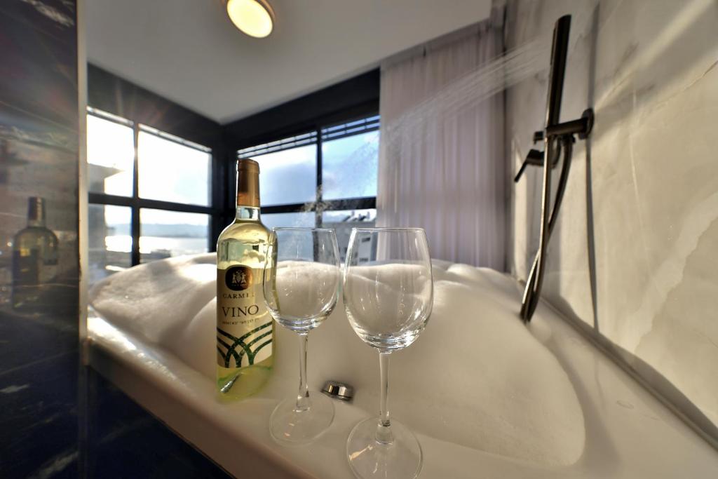 a bottle of wine and two wine glasses on a bath tub at סוויטות חוף האהבה in Haifa