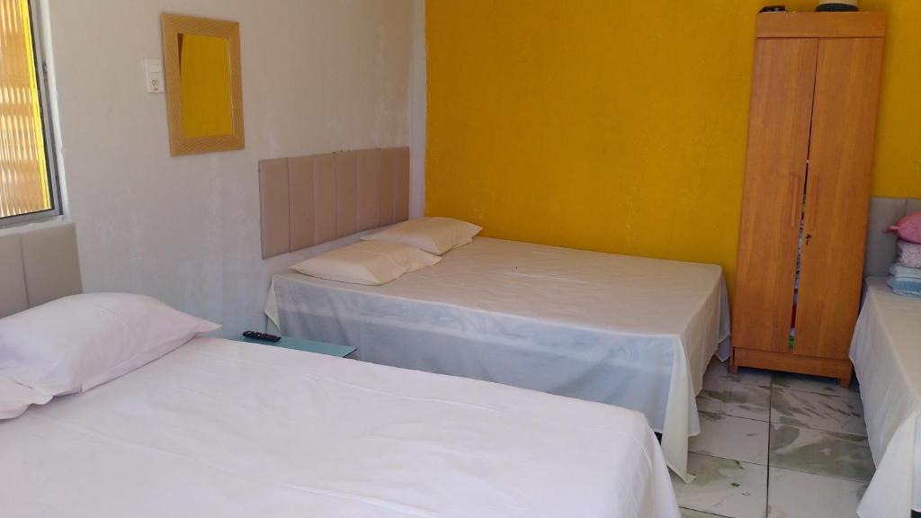 a room with two beds and a yellow wall at Chalé a beira mar ilhéus in Ilhéus