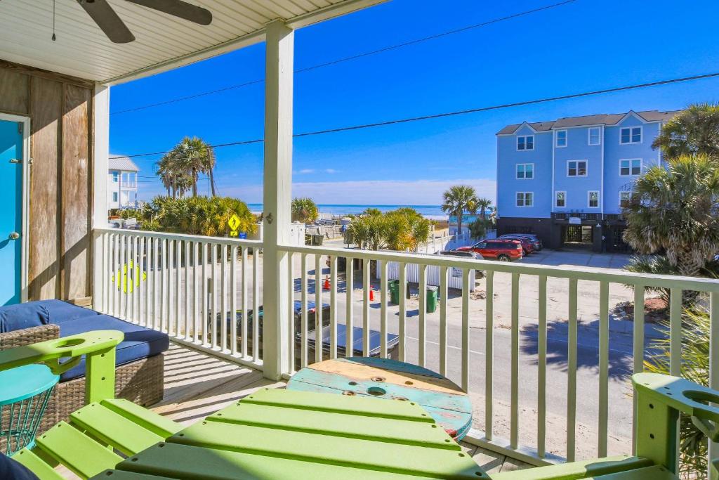 a balcony with green chairs and a view of a street at Hang 6 in Folly Beach