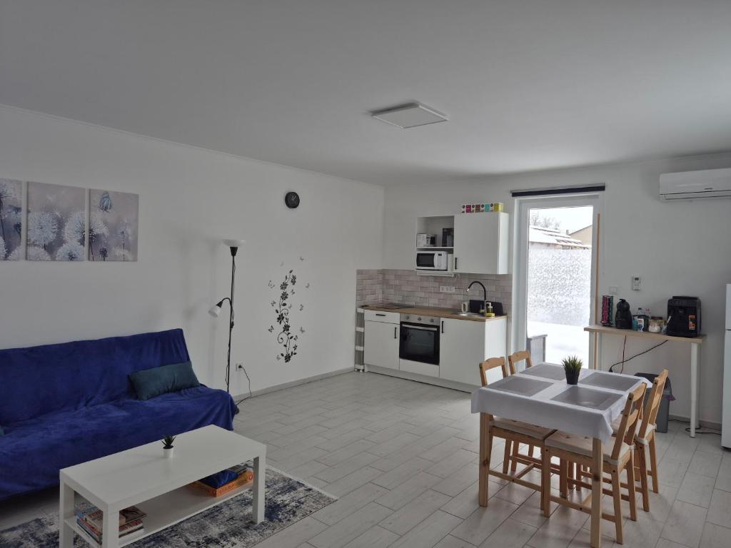 a living room with a blue couch and a table at Leander Apartman in Gyömrő