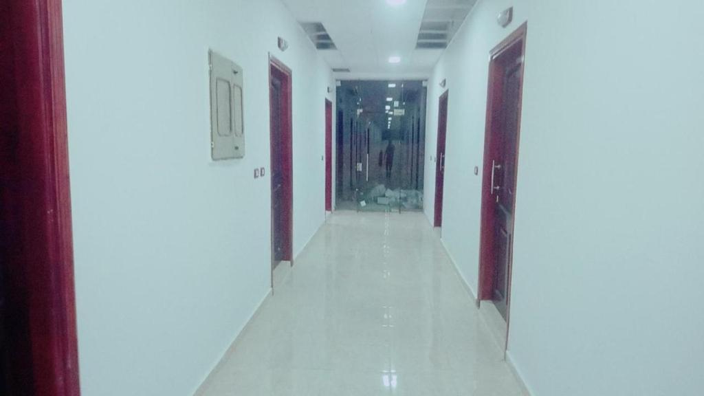 an empty hallway with white walls and red doors at Grand Plaza Apartment in Marsa Alam City