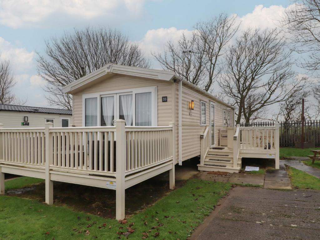 a tiny house with a porch and a deck at Homeslea 33 Millennium Gardens in Morpeth