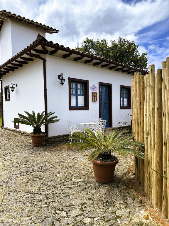 a white house with potted plants in front of it at Cadivó Chalé Lavras Novas in Ouro Preto