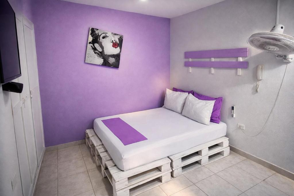 a small bedroom with a bed with purple walls at QuillaHost Guesthouse in Barranquilla