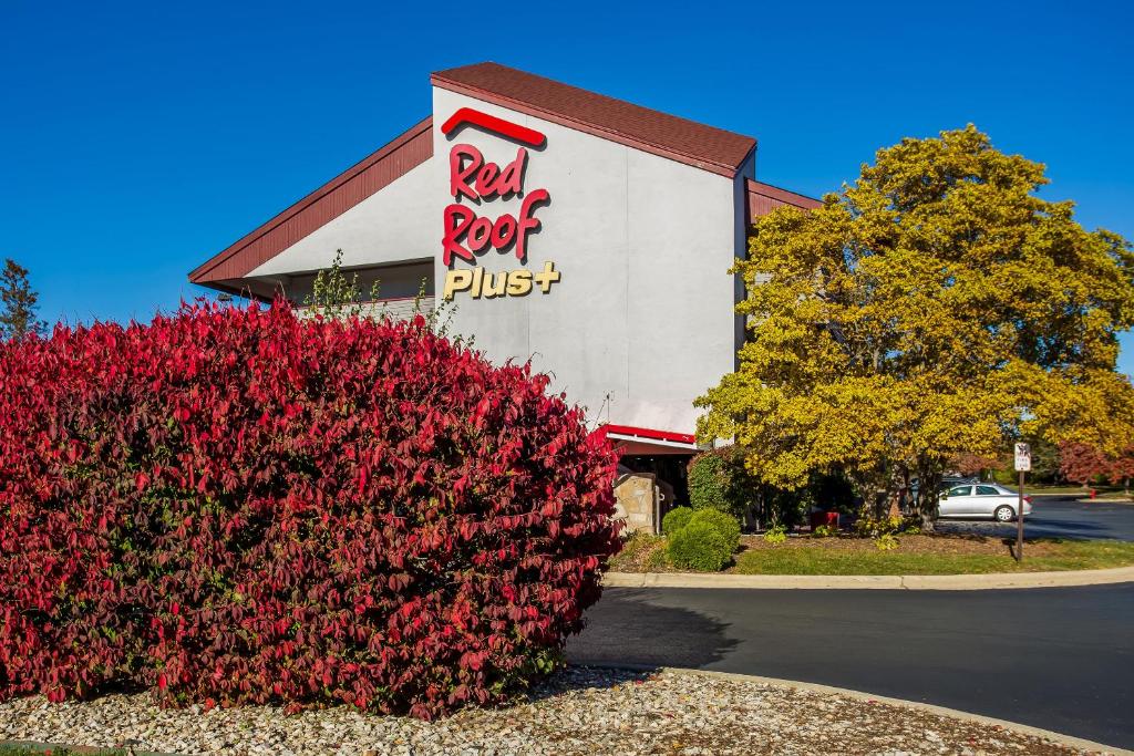 a restaurant with a red bush in front of a building at Red Roof Inn PLUS Chicago - Hoffman Estates in Hoffman Estates