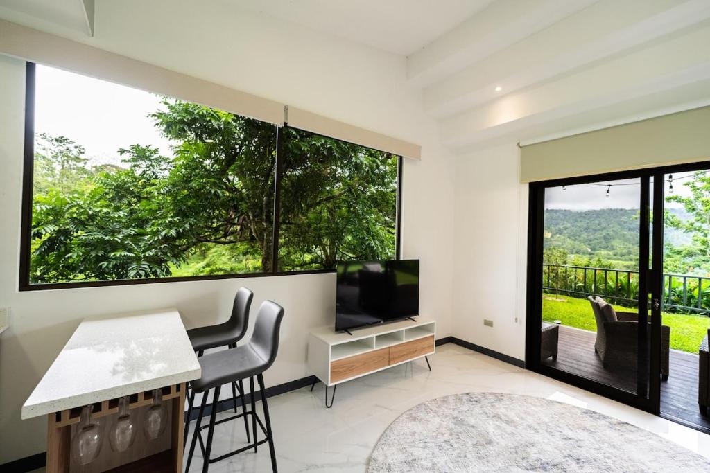 a living room with a television and a table and chairs at La Danta Lodge - Rio Celeste in Bijagua