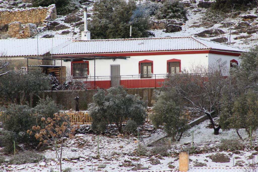 a white house with red trim in the snow at El Almendro de Fuentes Nuevas in Castril