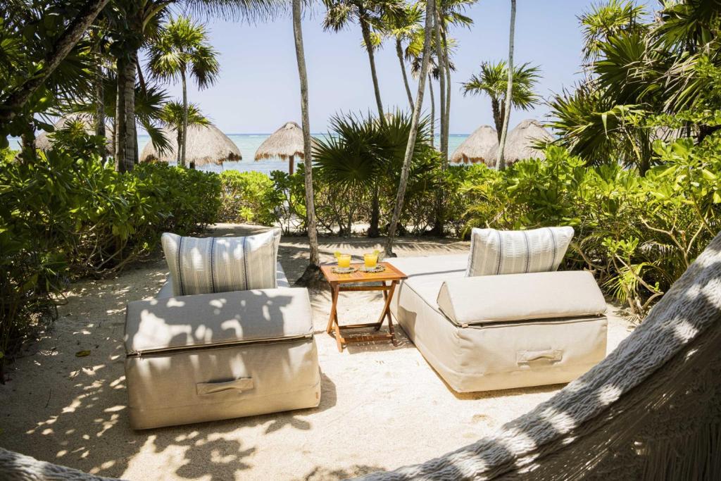 two lounge chairs and a coffee table on a beach at Beachfront Bliss Suite in Balcheil