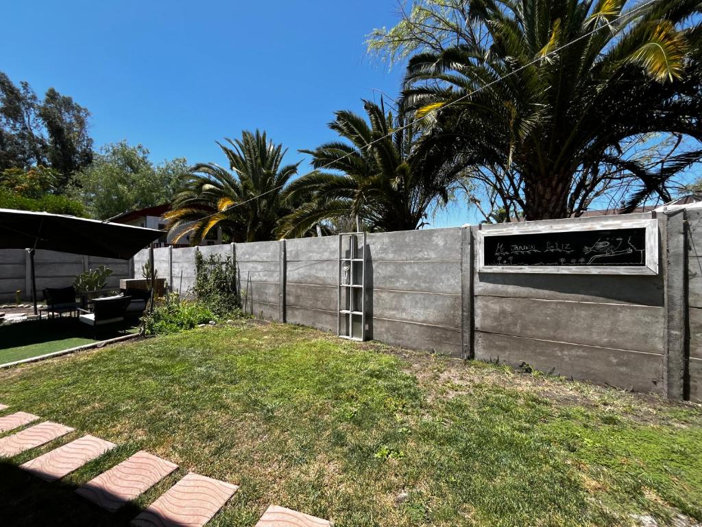 a fence with a ladder in a yard with palm trees at Mels House Batuco in El Cerrillo