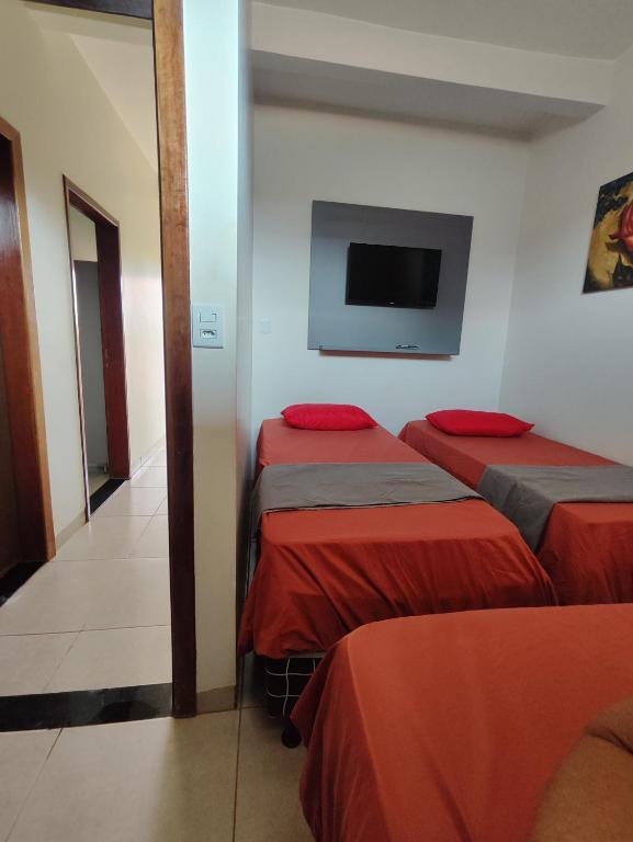 a room with two beds and a flat screen tv at Quarto Triplo Comercial - Queen's Hotel in Formosa
