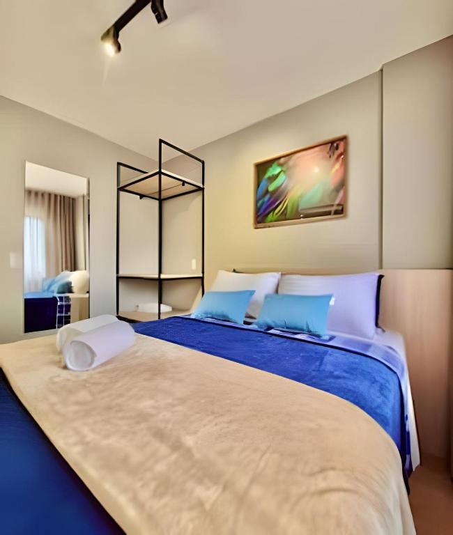a bedroom with a large bed with blue sheets at Studio Prime, no centro de CWB in Curitiba