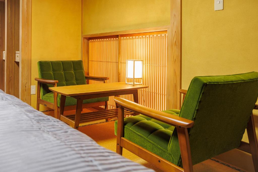 a room with a bed and two chairs and a table at North Nagano Inn in Iiyama