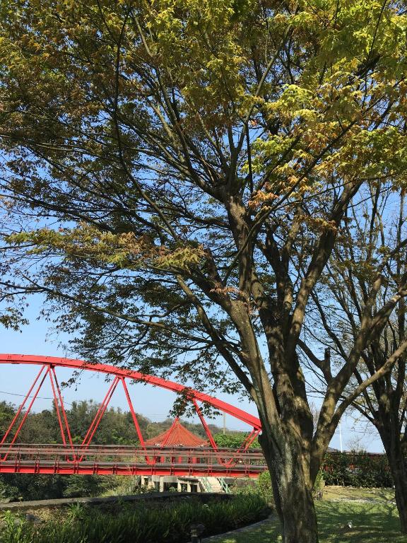 a red bridge with a tree in front of it at Rainbow Bridge B&amp;B in Sanzhi