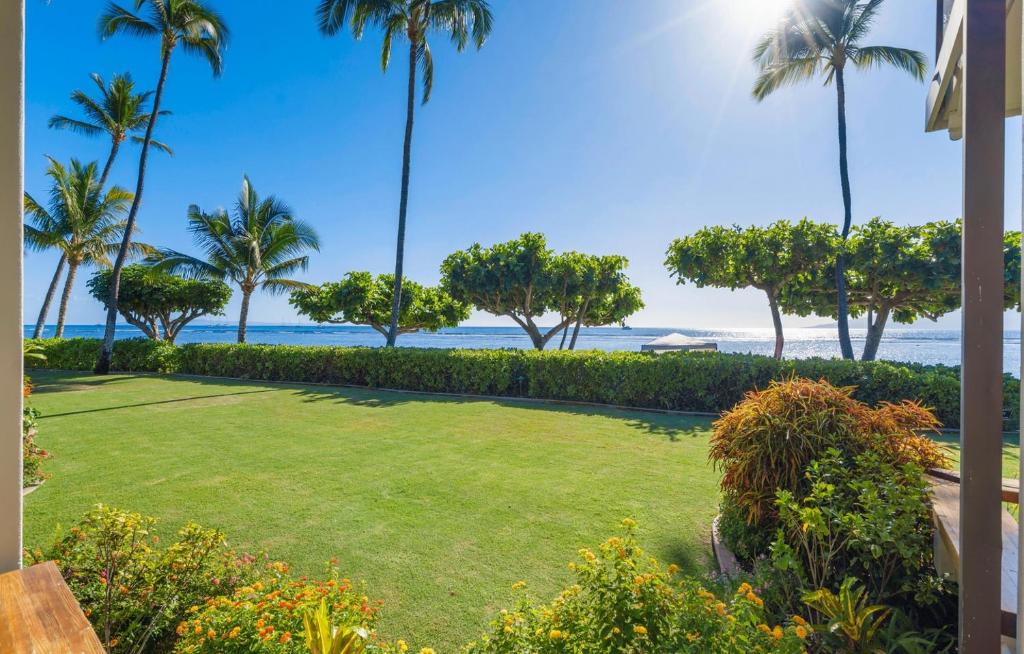 a lawn with palm trees and the ocean in the background at Puunoa Beach Estate in Lahaina