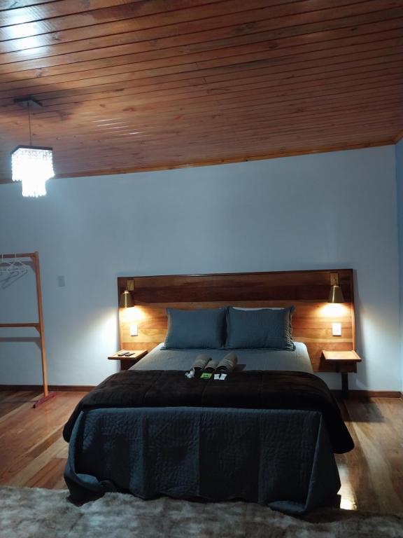 a bedroom with a large bed with a wooden headboard at Chalé Vila do Vento in Lavras Novas