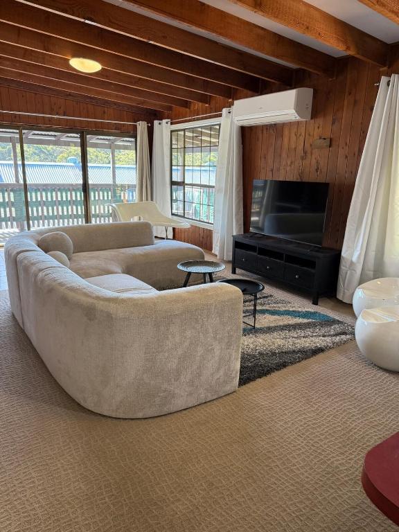 a living room with a couch and a television at Terrigal Cottage in Terrigal