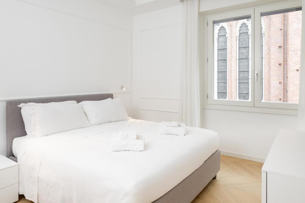 a white bedroom with a large bed with white sheets at Mamma Mia Holidays - Dimore Maggiori in Bologna
