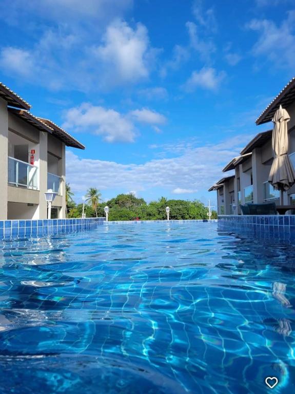 a swimming pool at a resort with blue water at Paraíso em Imbassaí in Imbassai