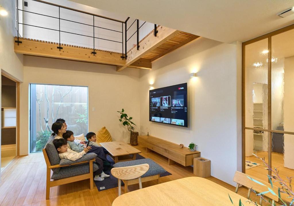 a family sitting in a living room watching tv at Cortile in Mitoyo