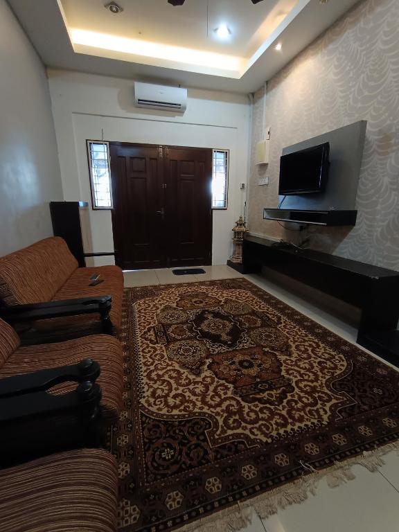 a living room with a couch and a flat screen tv at D Aida Homestay Bukit Katil in Kampong Bukit Katil