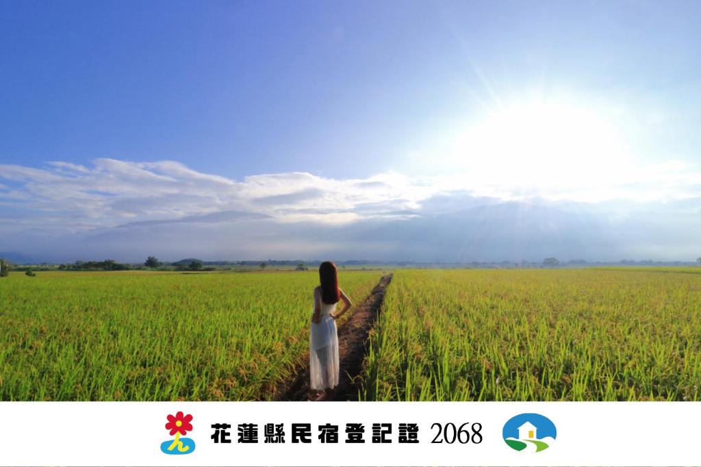 a woman walking down a road in a field at 玉里囍宿民宿 花蓮縣民宿2068號 in Yuli