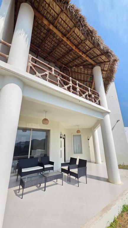 a patio with a balcony with chairs and tables at Casa Chaue in Tangolunda
