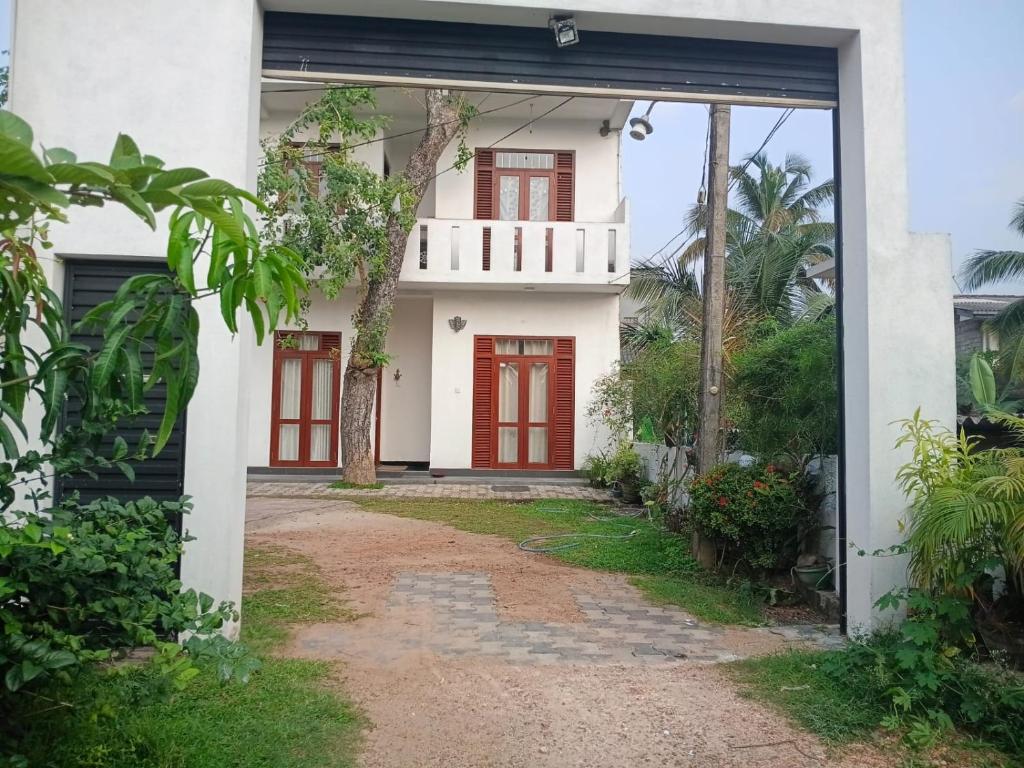 a white house with red doors and a driveway at The Grand Villa Malabe in Malabe