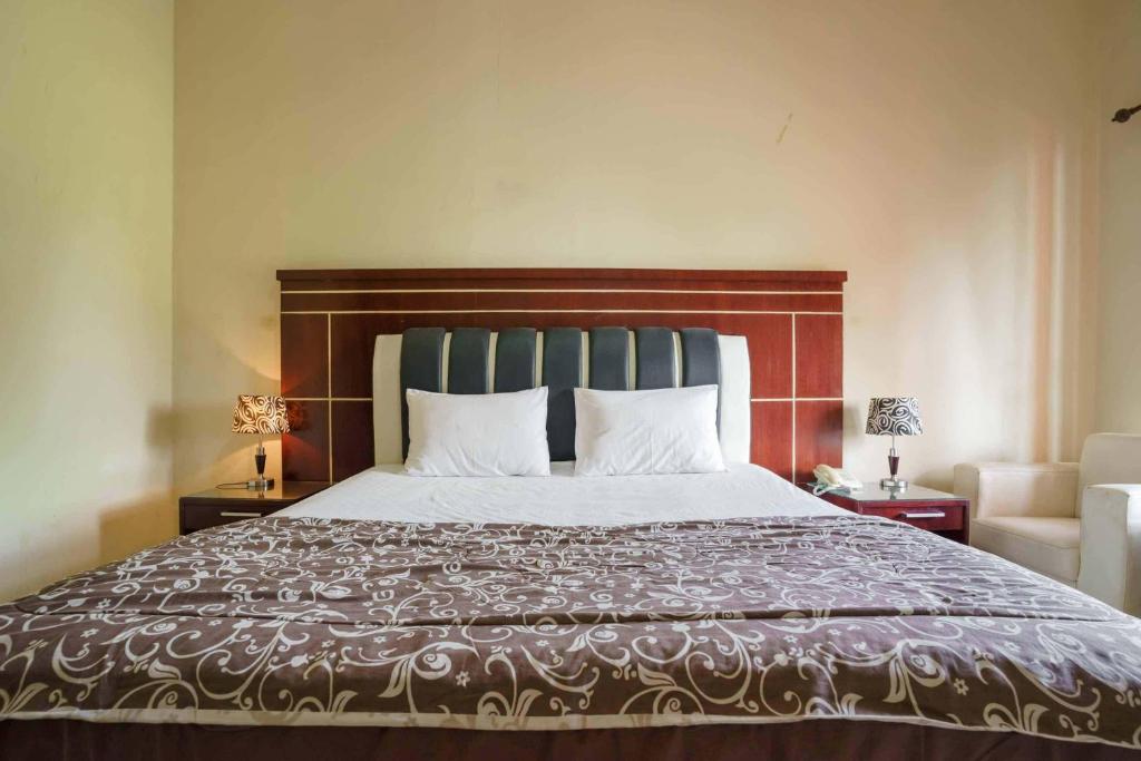 a bedroom with a large bed with a wooden headboard at Wisma Belerang Kalianda Lampung RedPartner in Kalianda