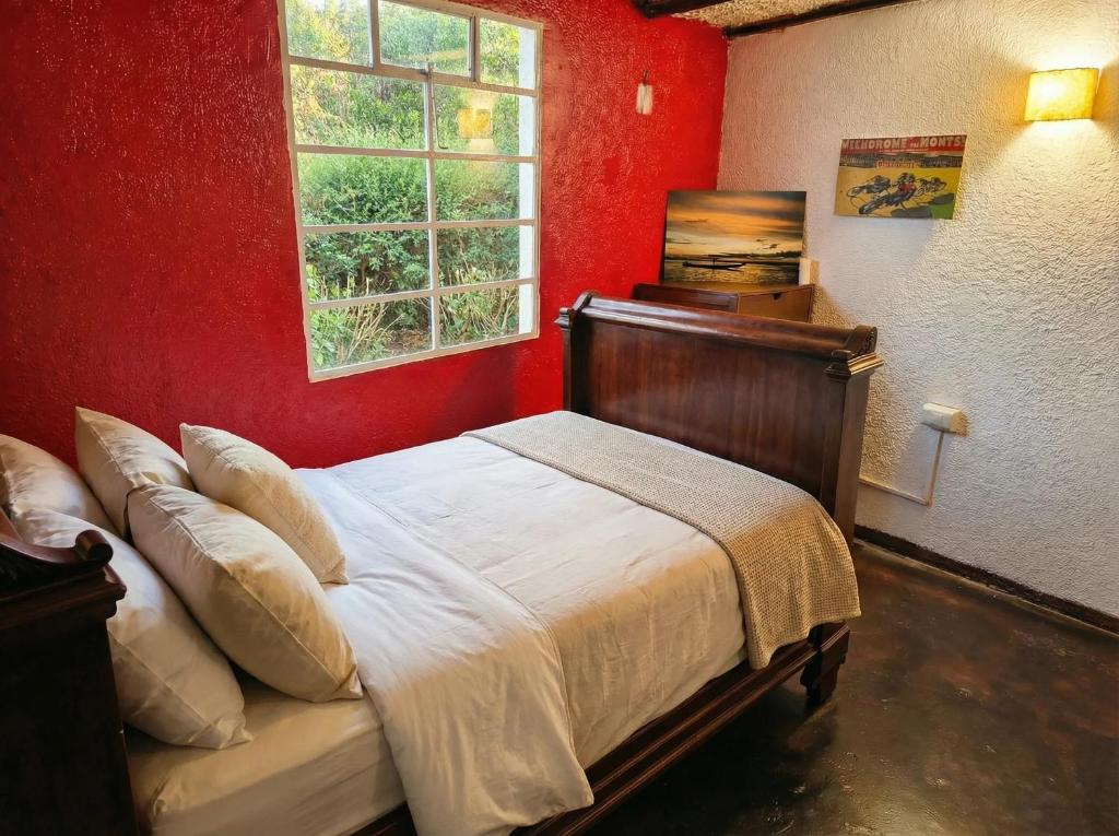 a bedroom with a bed with a red wall at Habitación cama doble con vista al bosque - 4 cuadras parque de Usaquen in Bogotá