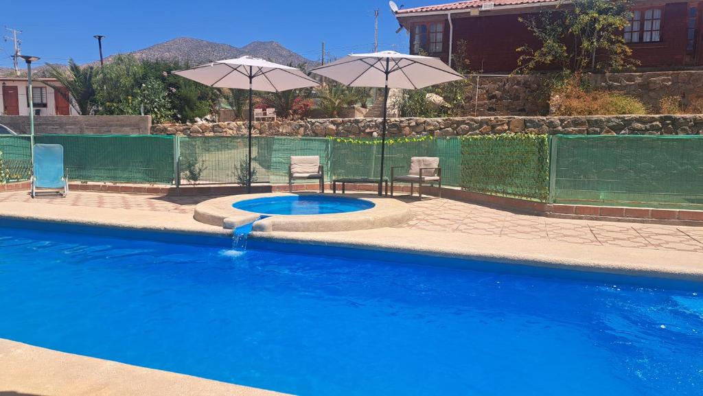 a swimming pool with two chairs and an umbrella at Panul Ovalle in Panulcillo