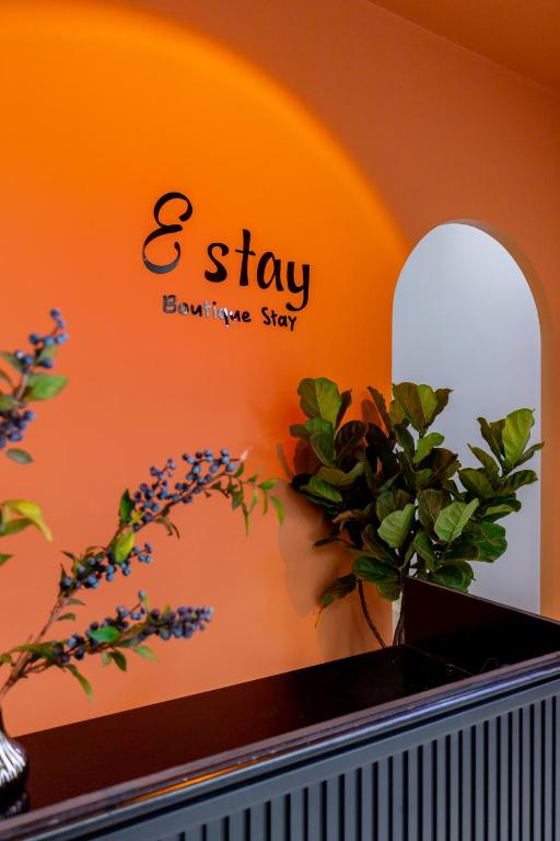 a sign on a wall with a plant on a shelf at E Stay Boutique in Vung Tau