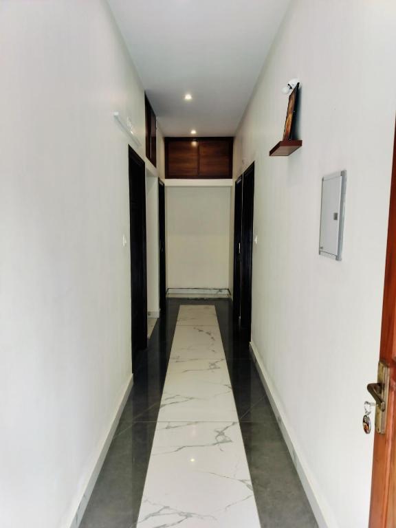 a hallway with white walls and a tile floor at Canan suites in Trivandrum