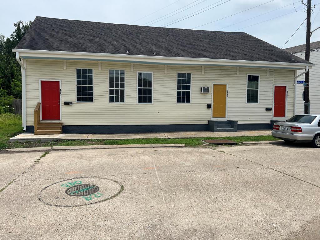 a white house with red doors and a car parked in front at Trisuites 2 in New Orleans