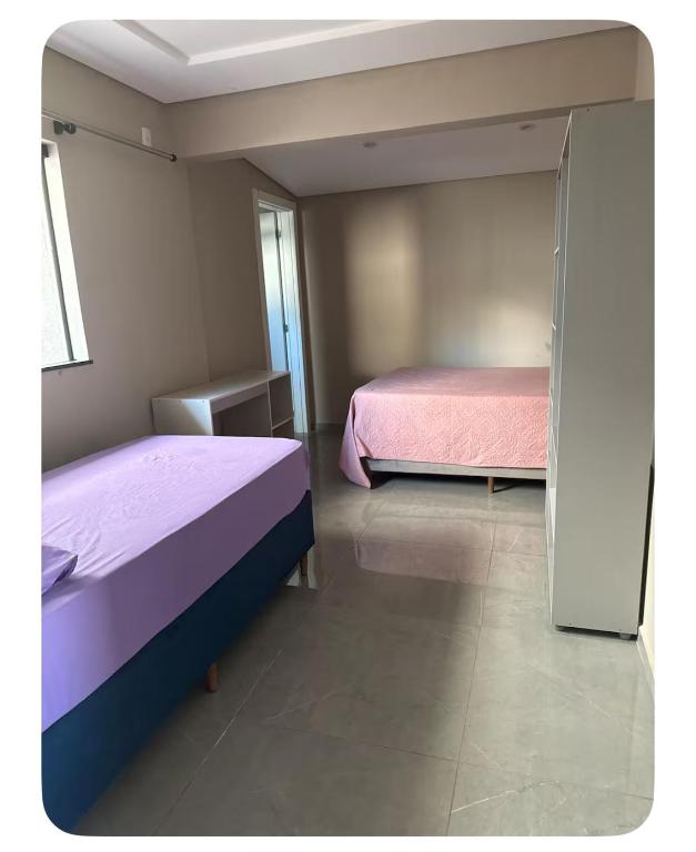 a bedroom with two beds and a sliding glass door at Apartamento Casa pontarolo in Guarapuava