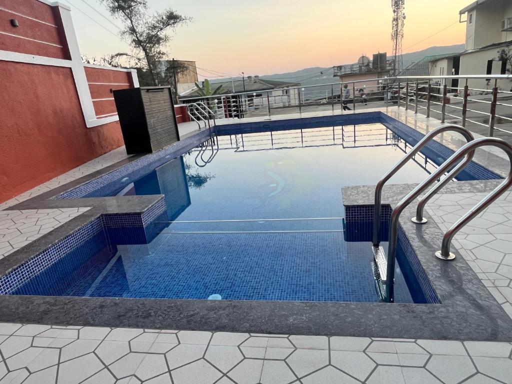 a swimming pool with a bench next to a building at Hotel Soham Retreat in Mahabaleshwar