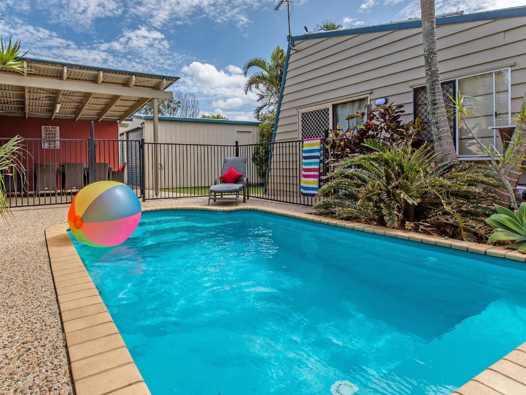 a swimming pool with a beach ball in front of a house at Surf Club House, Pet Friendly, Sunshine Coast, Holiday House, Marcoola in Marcoola