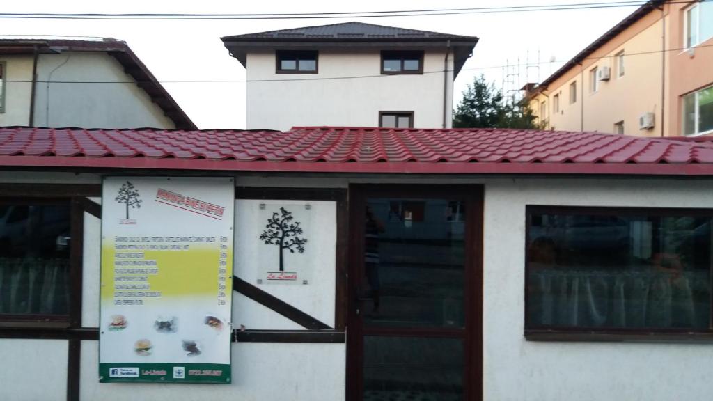 um edifício com um telhado de azulejos vermelhos e uma porta em La Livada em Otopeni